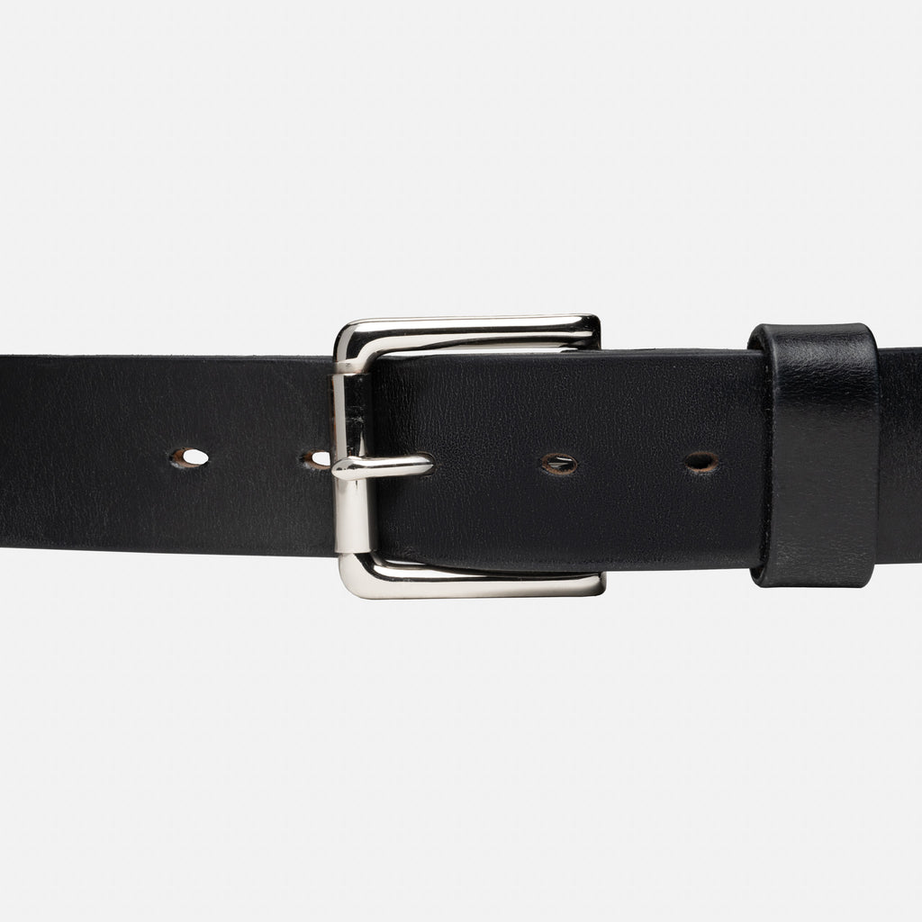 Black leather belt with a silver buckle on a light gray background